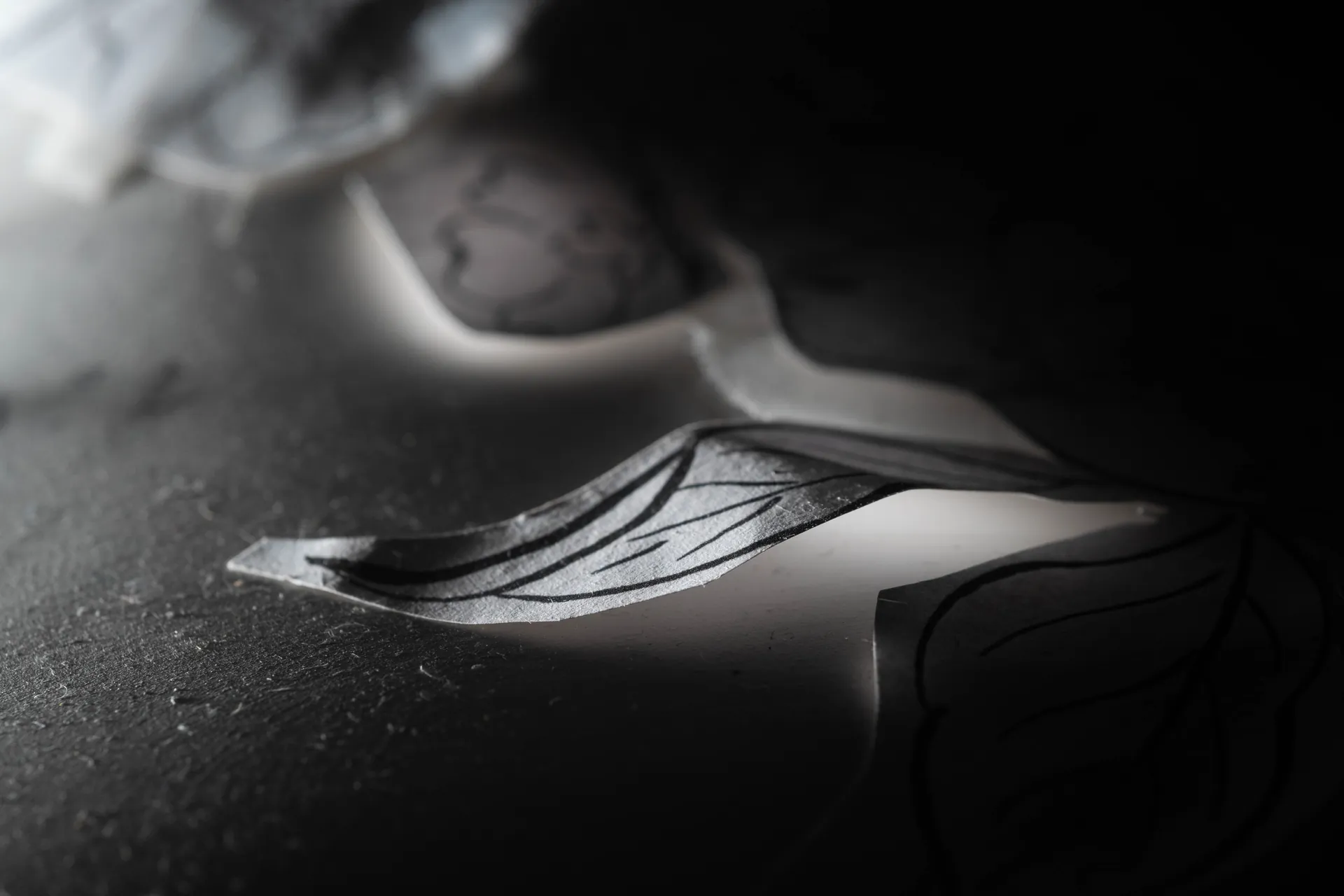 Tesson de faïence décorée sur un plan de travail sombre, motif peint à la main, clair-obscur