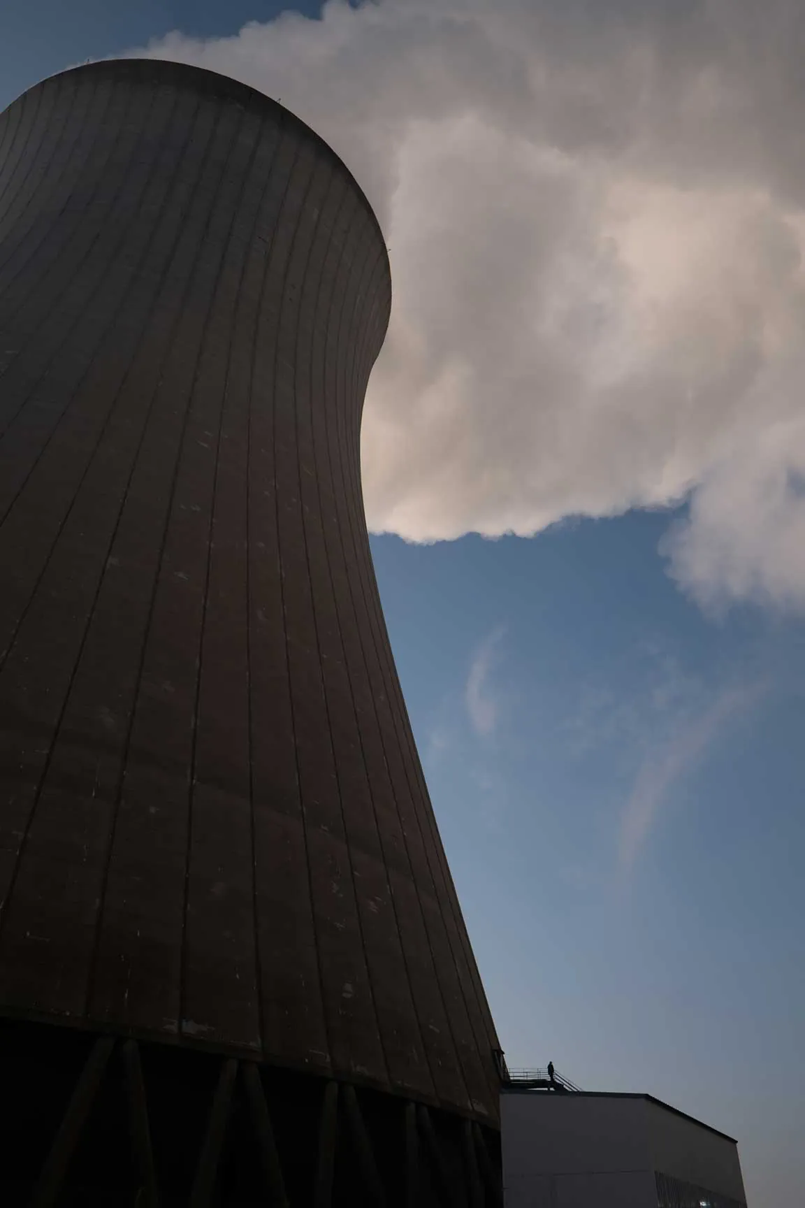 Tour de refroidissement nucléaire en contre-plongée, panache de vapeur sur ciel bleu