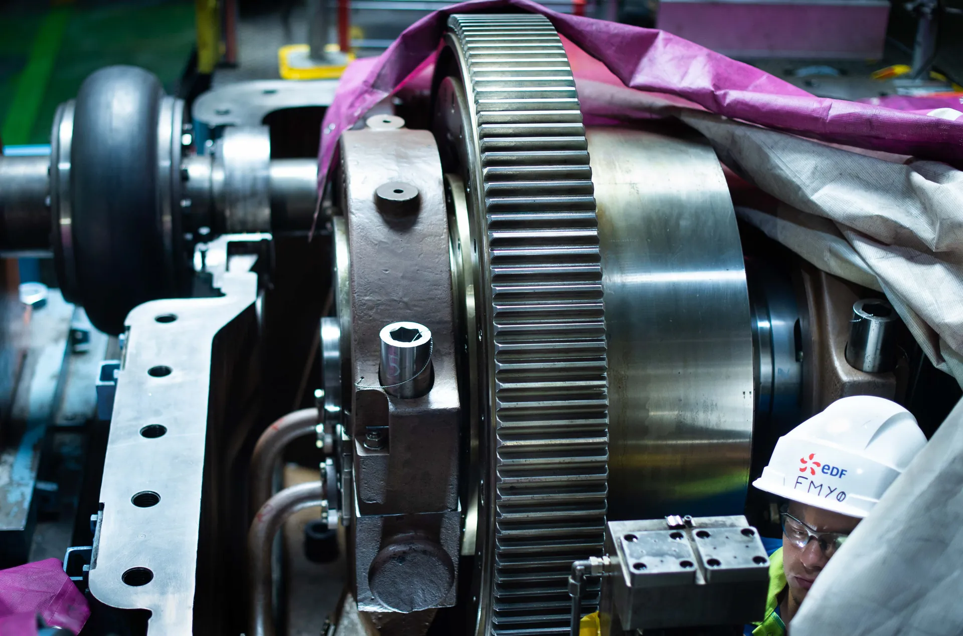 Engrenage et rotor de turbine en maintenance, casque EDF au premier plan, centrale nucléaire