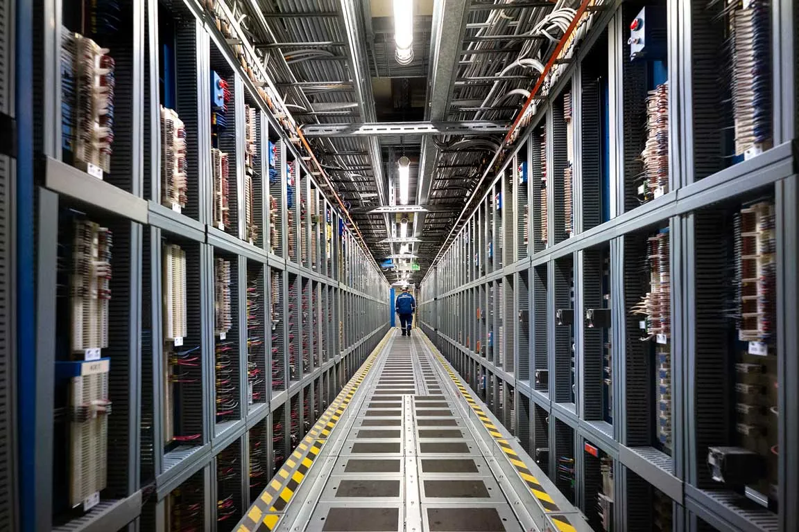 Technicien marchant dans le couloir d'armoires électriques d'une centrale nucléaire, perspective symétrique