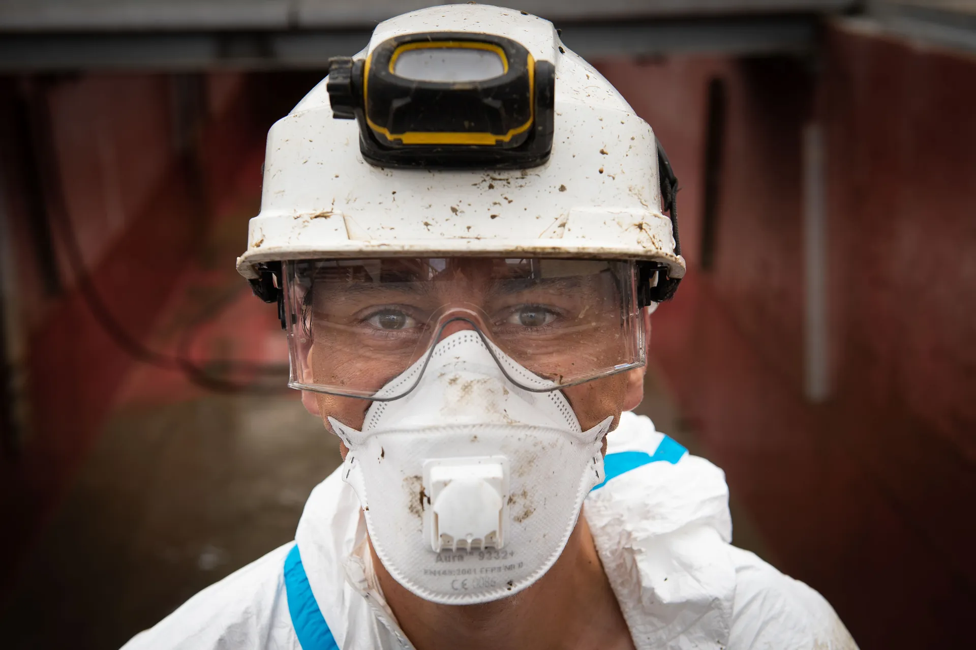 Technicien casqué en combinaison bleue branchant un connecteur industriel, flou de mouvement, centrale nucléaire