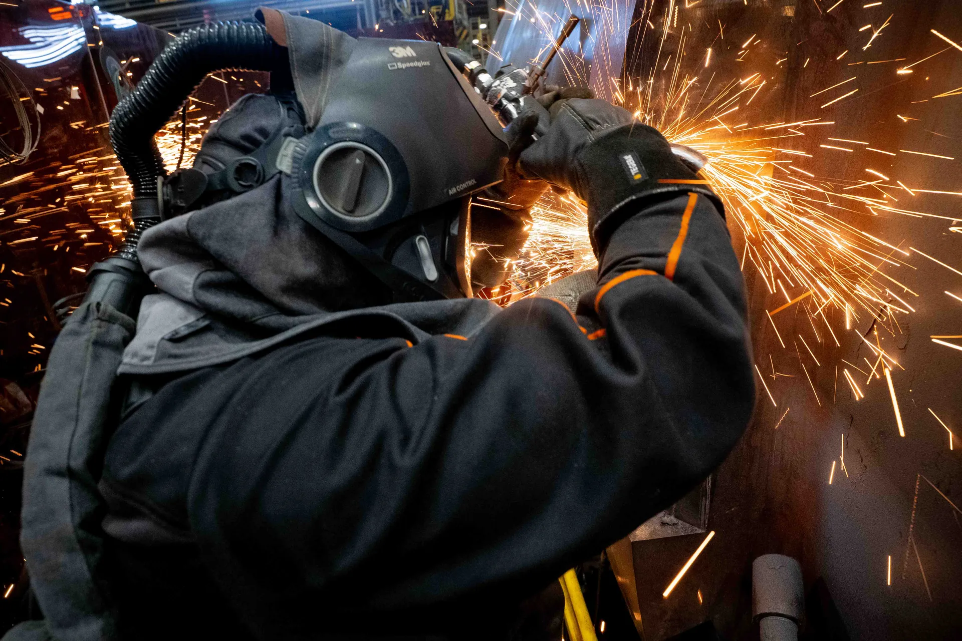 Soudeur équipé d'un masque respiratoire 3M Speedglas projetant une gerbe d'étincelles sur une structure métallique