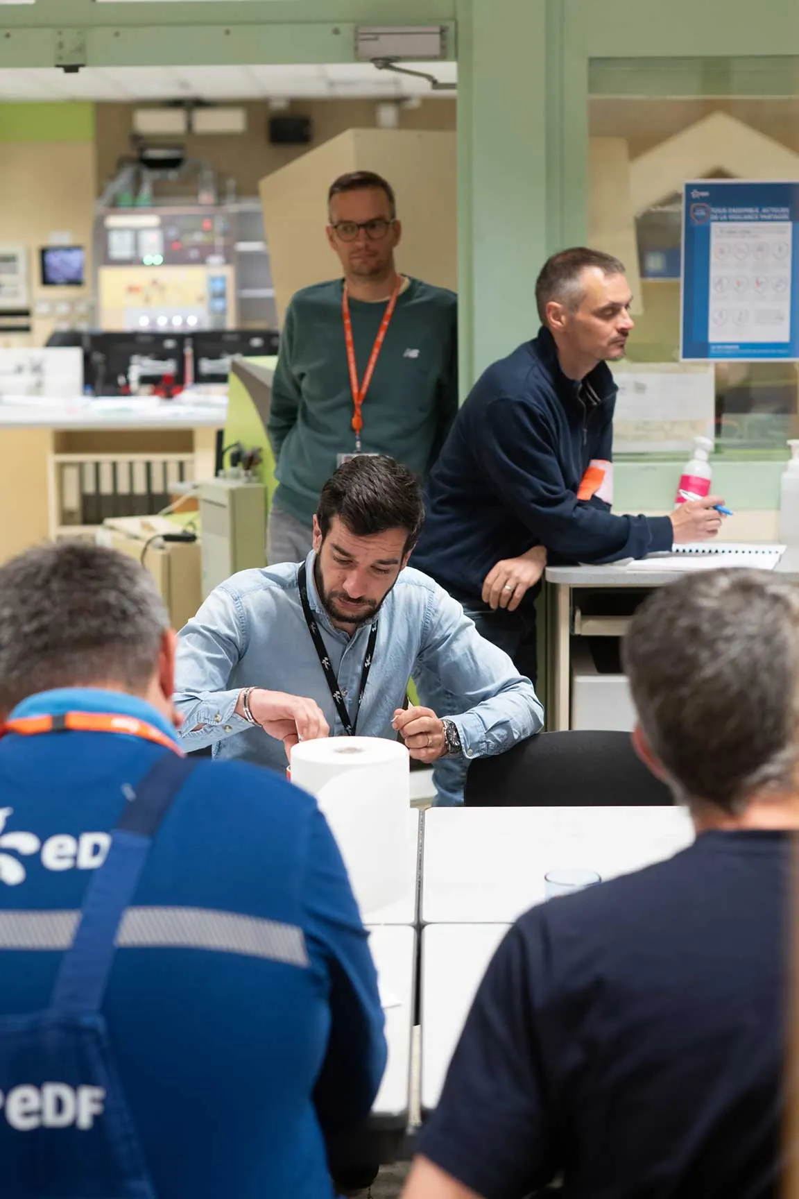 Briefing d'équipe en salle de commande, techniciens EDF en tenue de travail