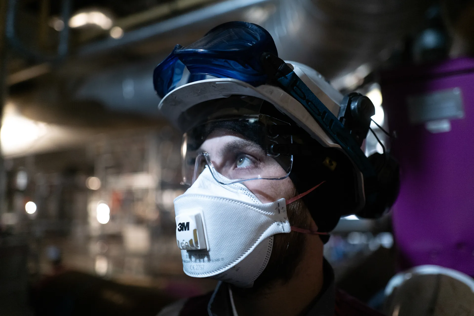 Portrait rapproché d'un technicien casqué avec masque FFP3 et lunettes de protection en centrale nucléaire