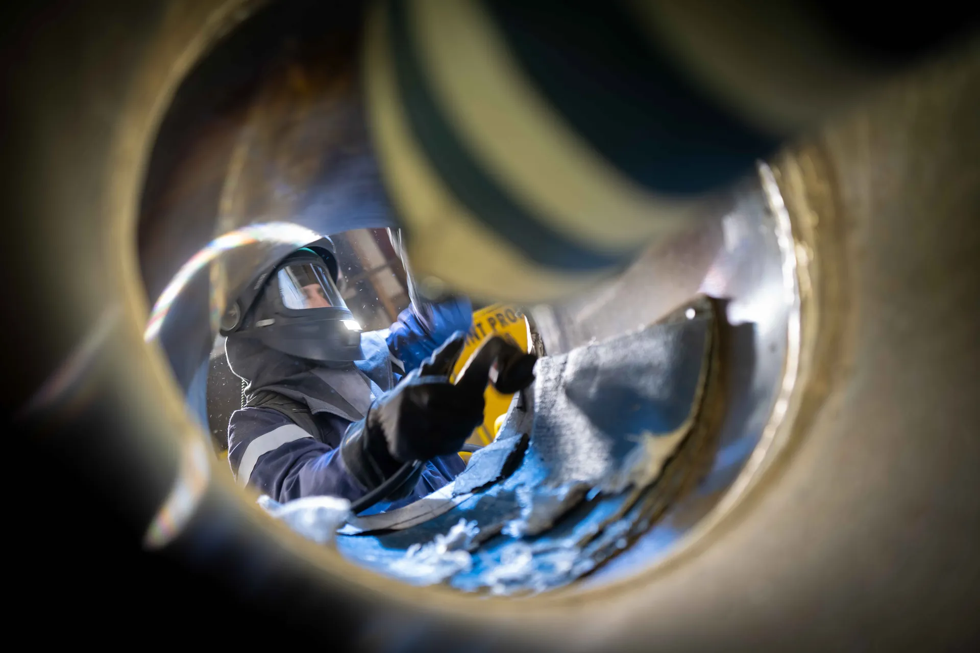 Portrait frontal d'un ouvrier en casque blanc taché, masque FFP3 et lunettes de protection, chantier nucléaire