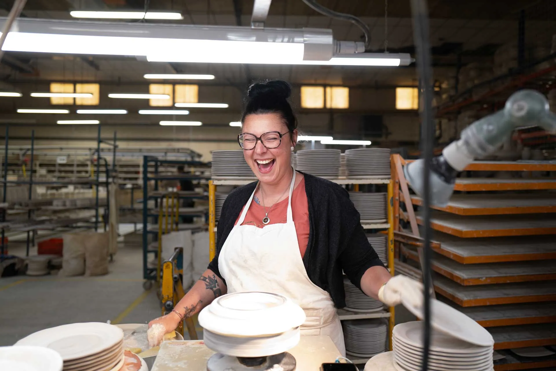 Ouvrier accoudé à un chariot de gazettes jaune, regard franc, atelier de la Faïencerie de Gien