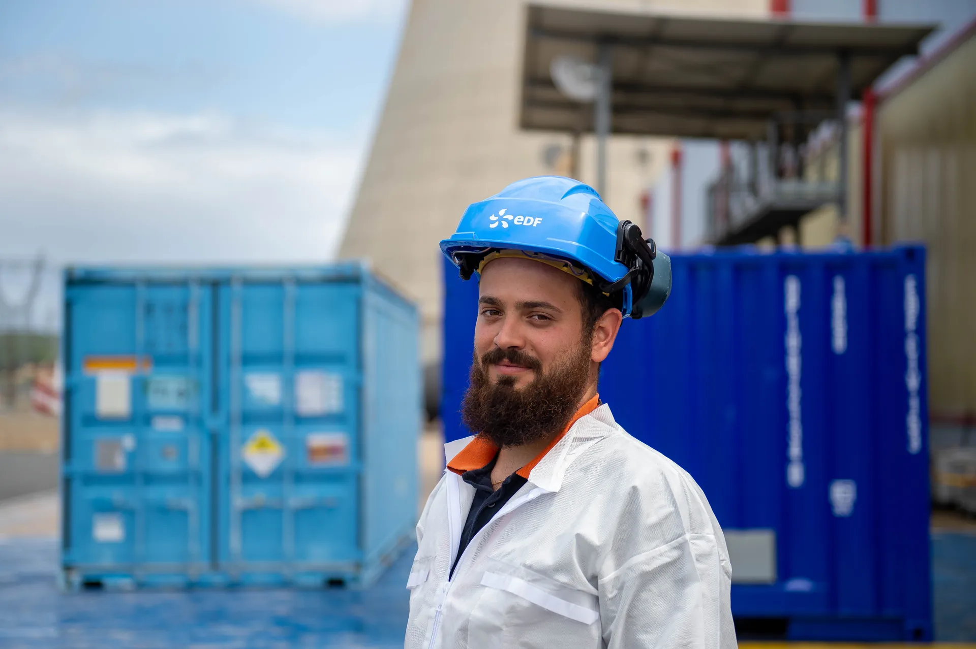 Jeune agente d'entretien souriante en blouse bleue avec chariot de nettoyage dans un couloir de centrale nucléaire