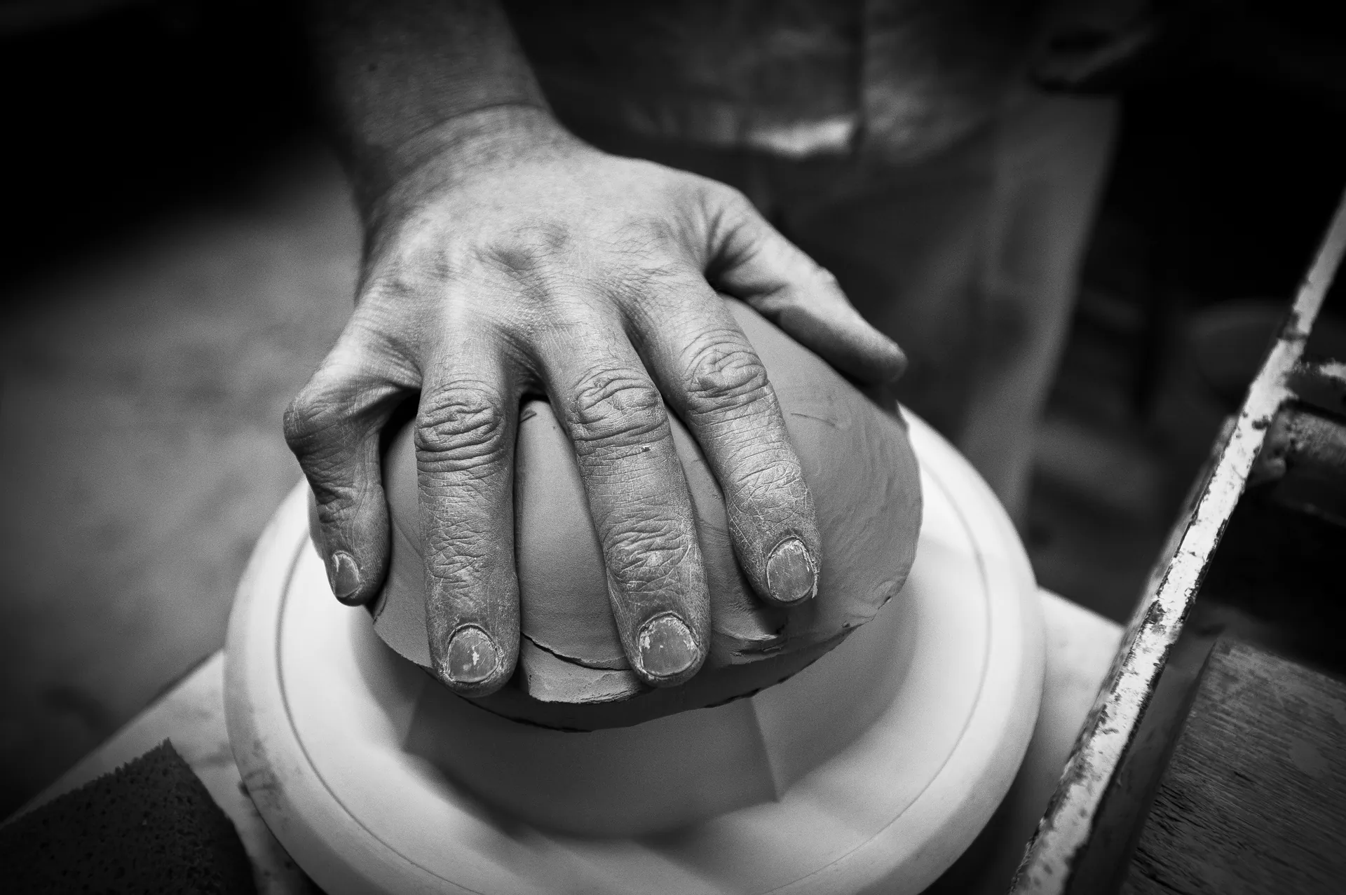 Main tenant un pinceau traçant le filet sur le bord d'une assiette en faïence blanche