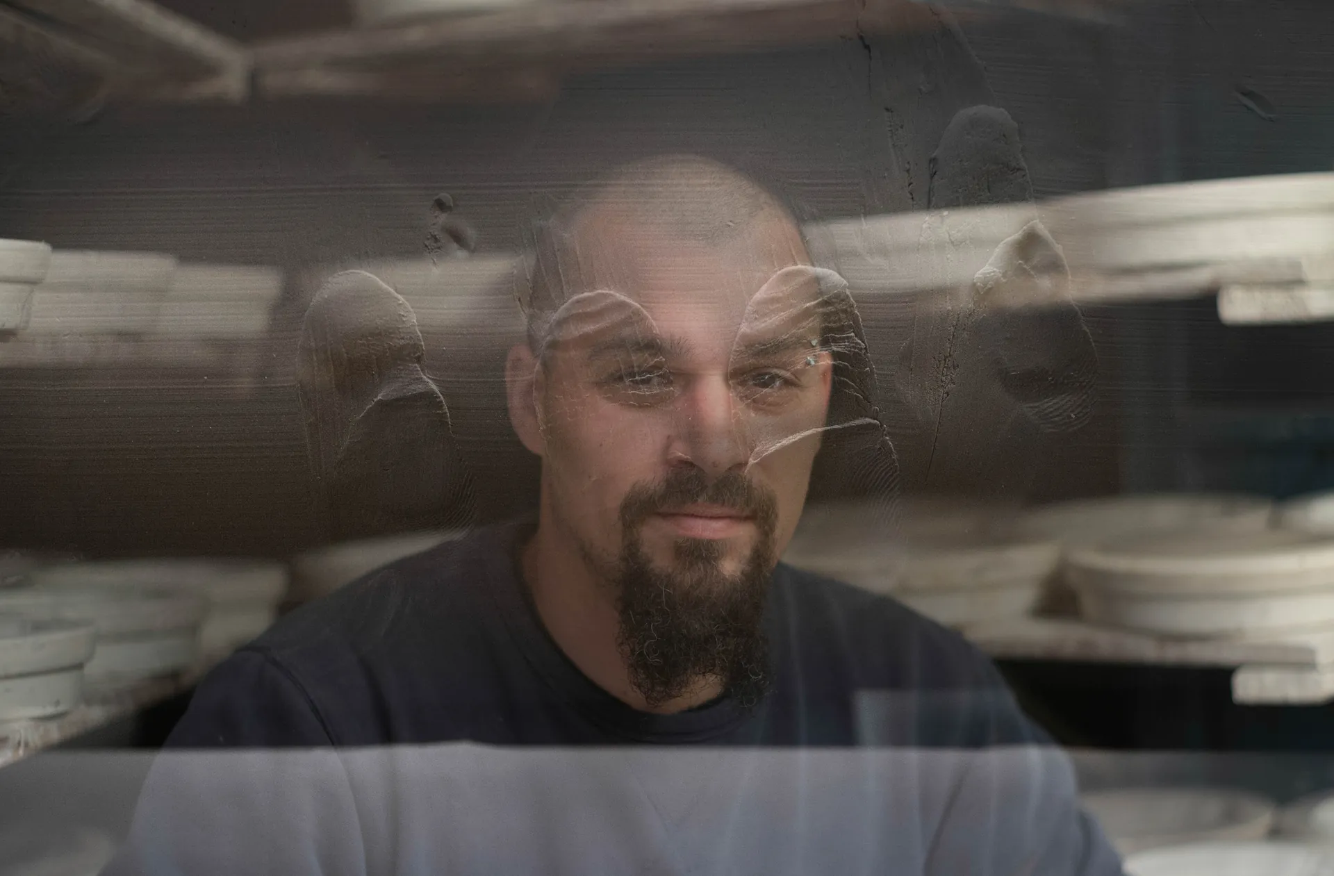 Ouvrière en blouse blanche tenant une porte industrielle noire, hublot jaune en arrière-plan