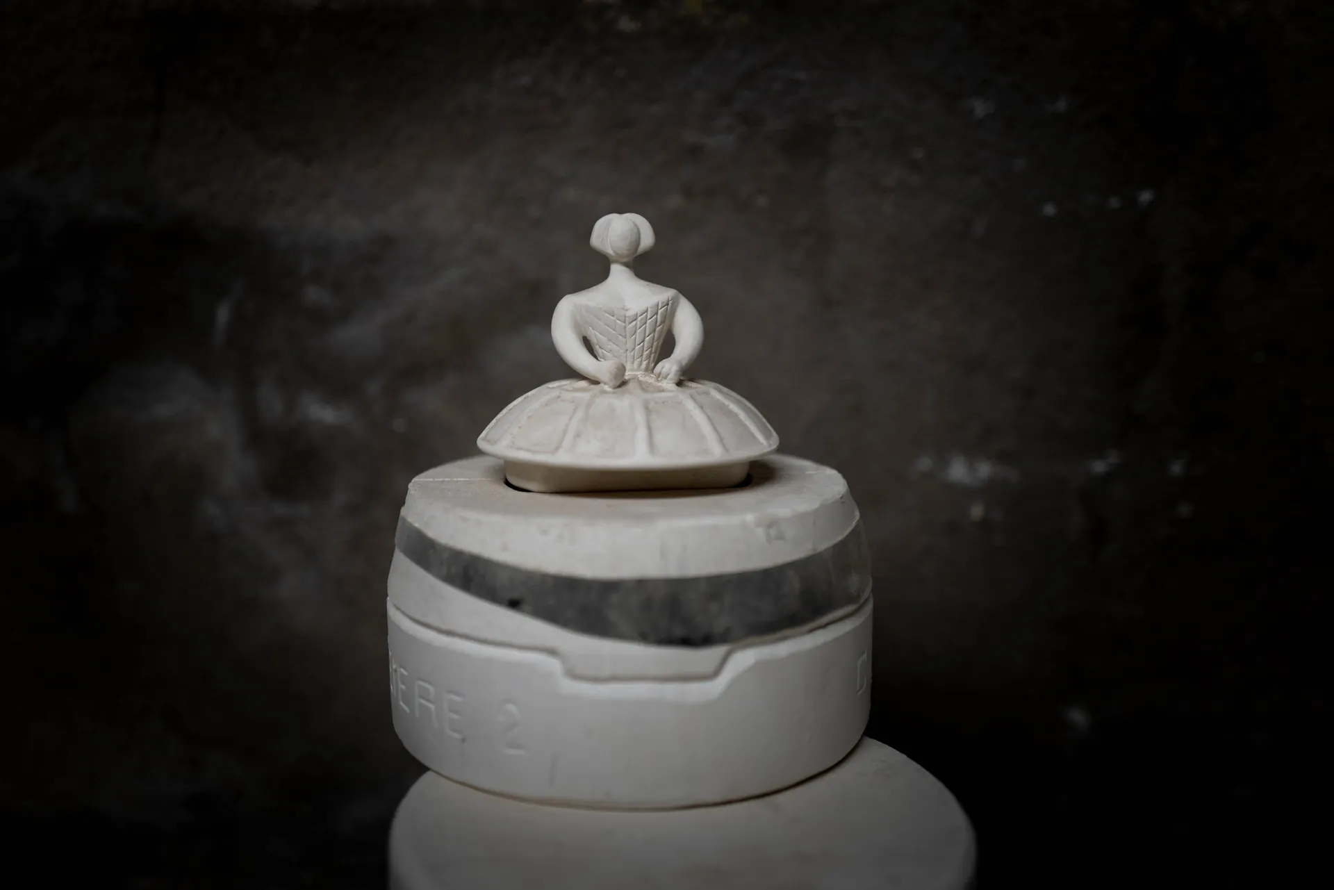 Pyramide de cylindres en terre crue empilés sur fond noir, composition nocturne