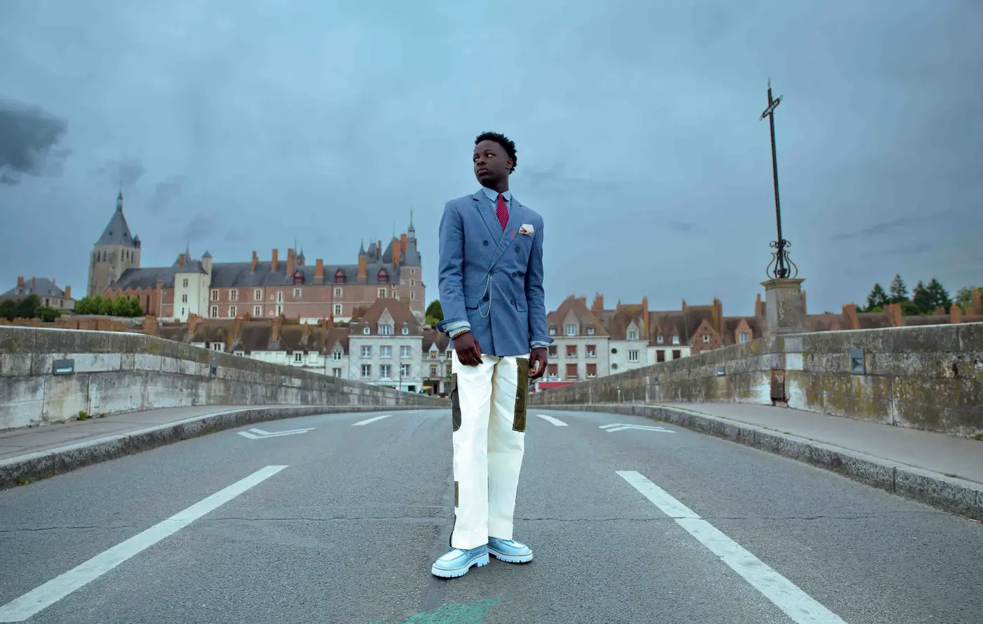 Basketteur en costume trois-pièces posant devant un mur tagué